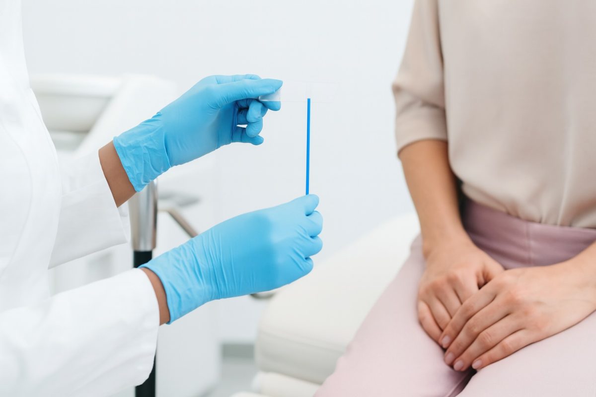 Healthcare provider preparing a swab for a chlamydia test while the patient sits with her hands folded on her lap.