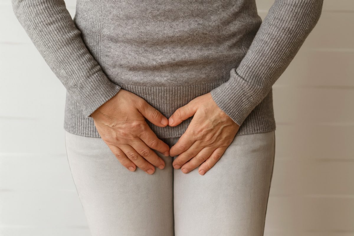 Person holding their lower abdomen, showing discomfort commonly associated with genital swelling or pelvic pain.