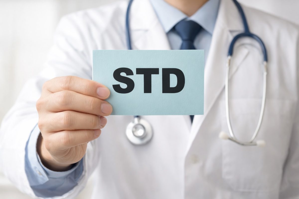 seorang doktor memegang kertas bertulis "STD"