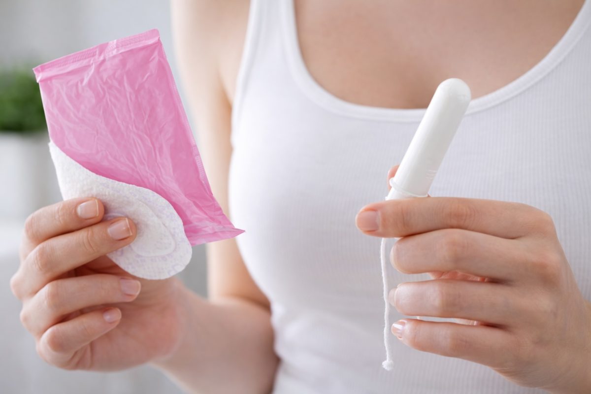Woman holding sanitary pad and tampon, representing menstrual hygiene and proper intimate care practices