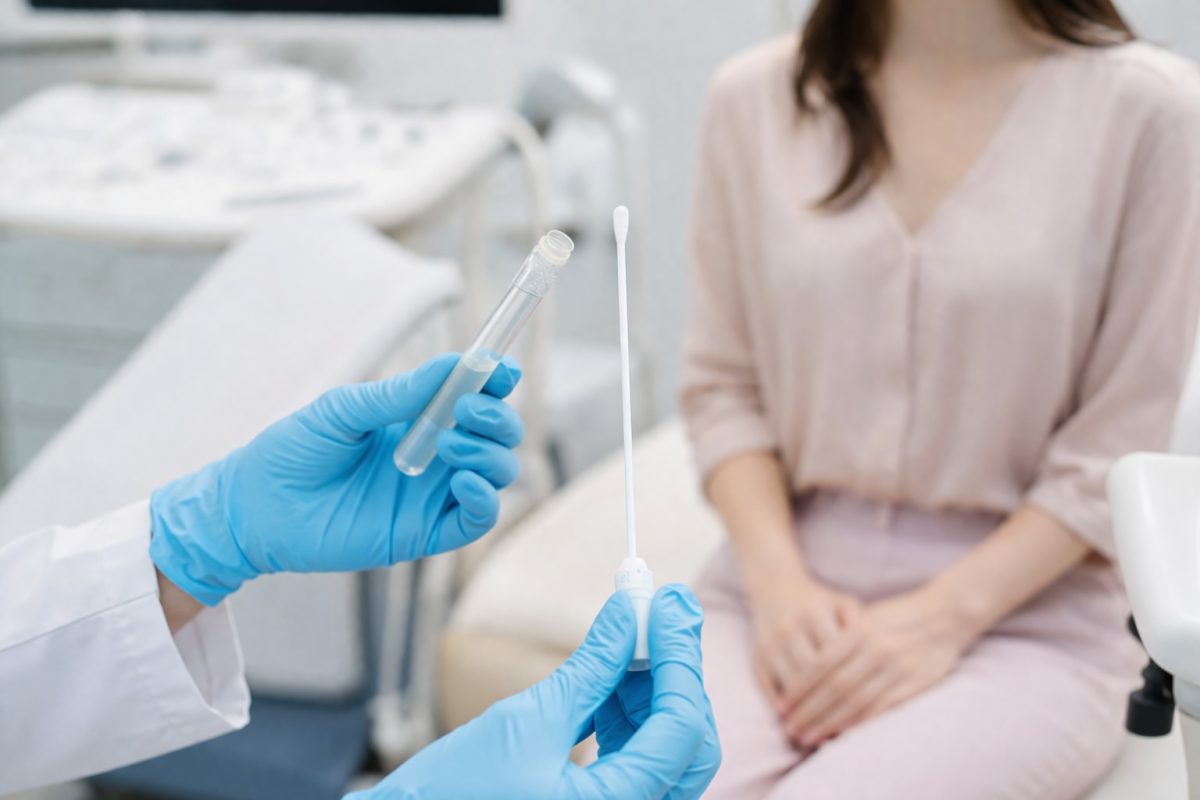 Medical professional holding swab and sample tube, representing STD testing and early detection procedures