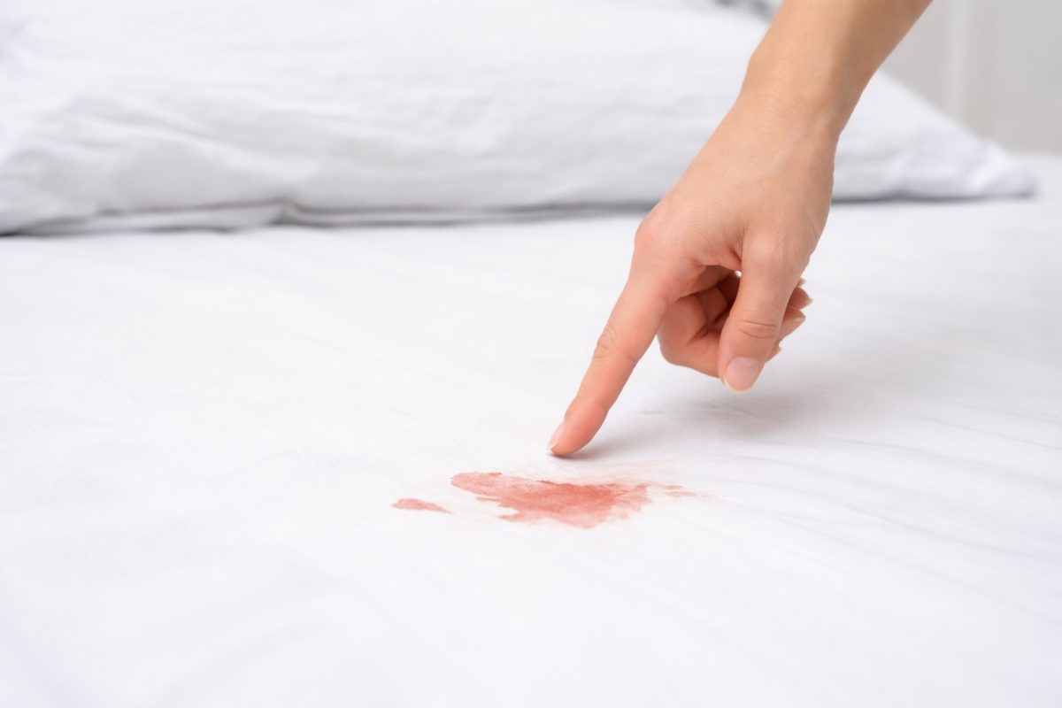 Close-up of blood stain on bedsheet, representing abnormal bleeding or possible pelvic inflammatory disease warning sign