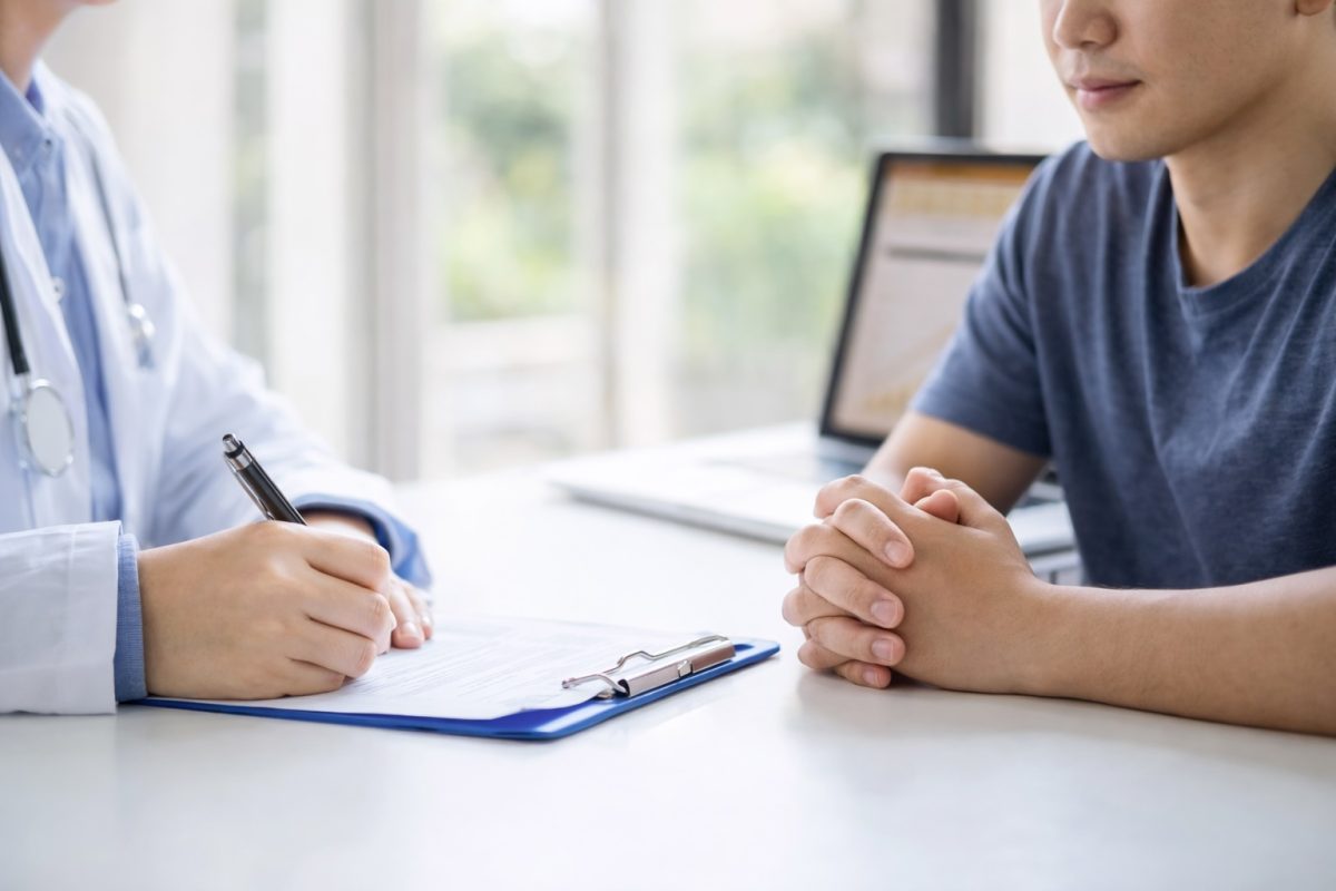 Doctor consulting patient at clinic desk, discussing symptoms and possible STD testing for accurate diagnosis